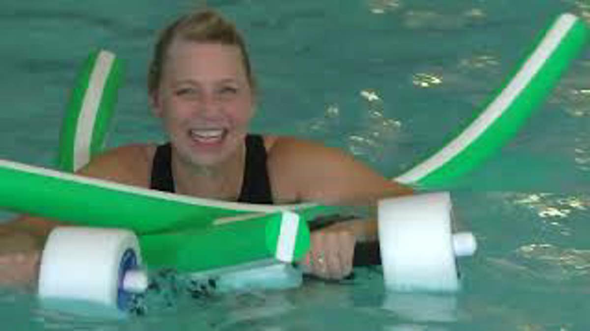 A woman in a pool holding on to a floaty. 