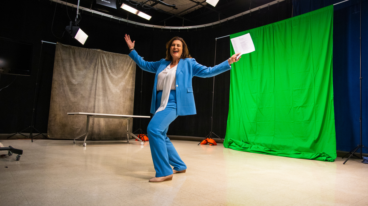 A woman with her arms out standing in front of two tarps. 