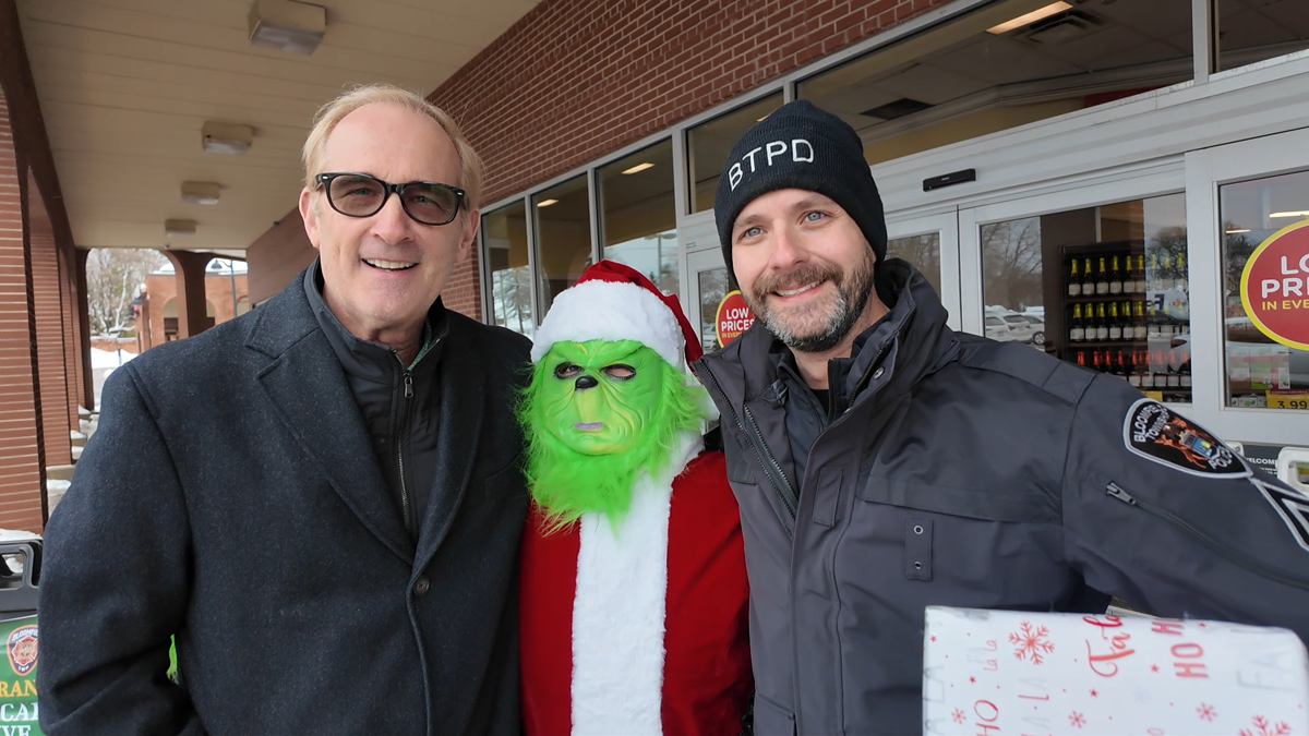 Supervisor Mike McCready and BTPD Sgt Soley with the Grinch dressed like Santa outside of a grocery store entrance.