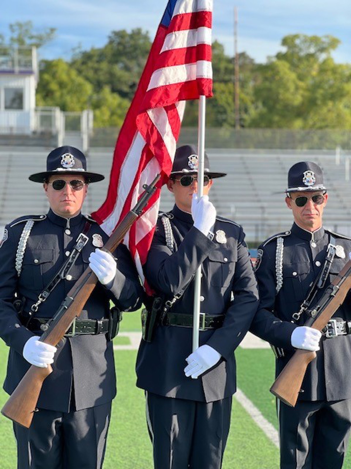 Three honor guard members holding rifles and an American flag. 