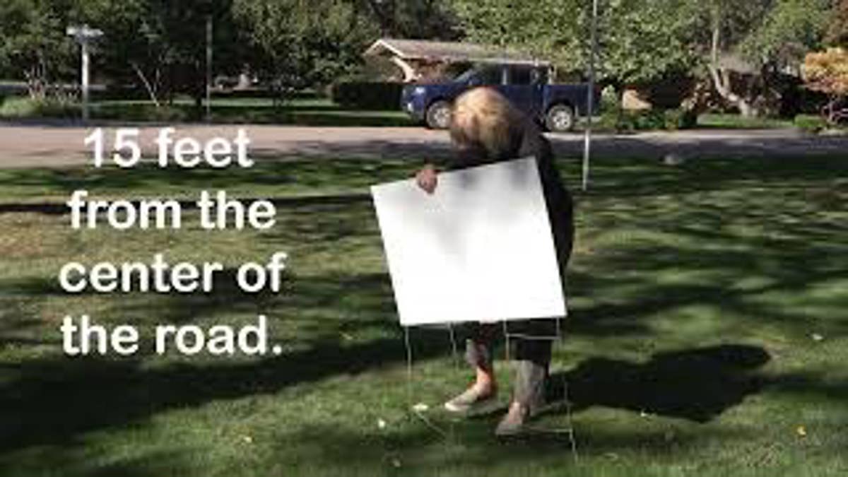 A person planting a sign into the ground. 