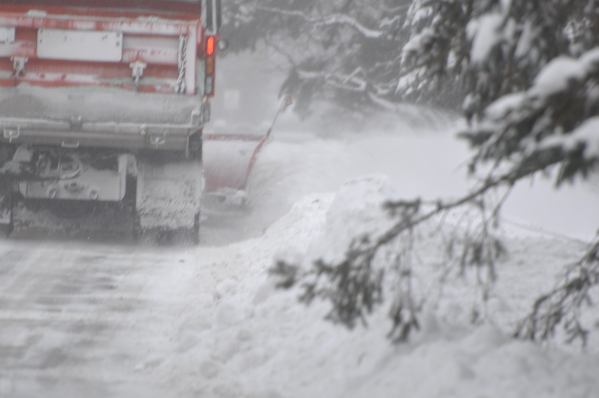 Snowplow that is plowing snow off of the road.  