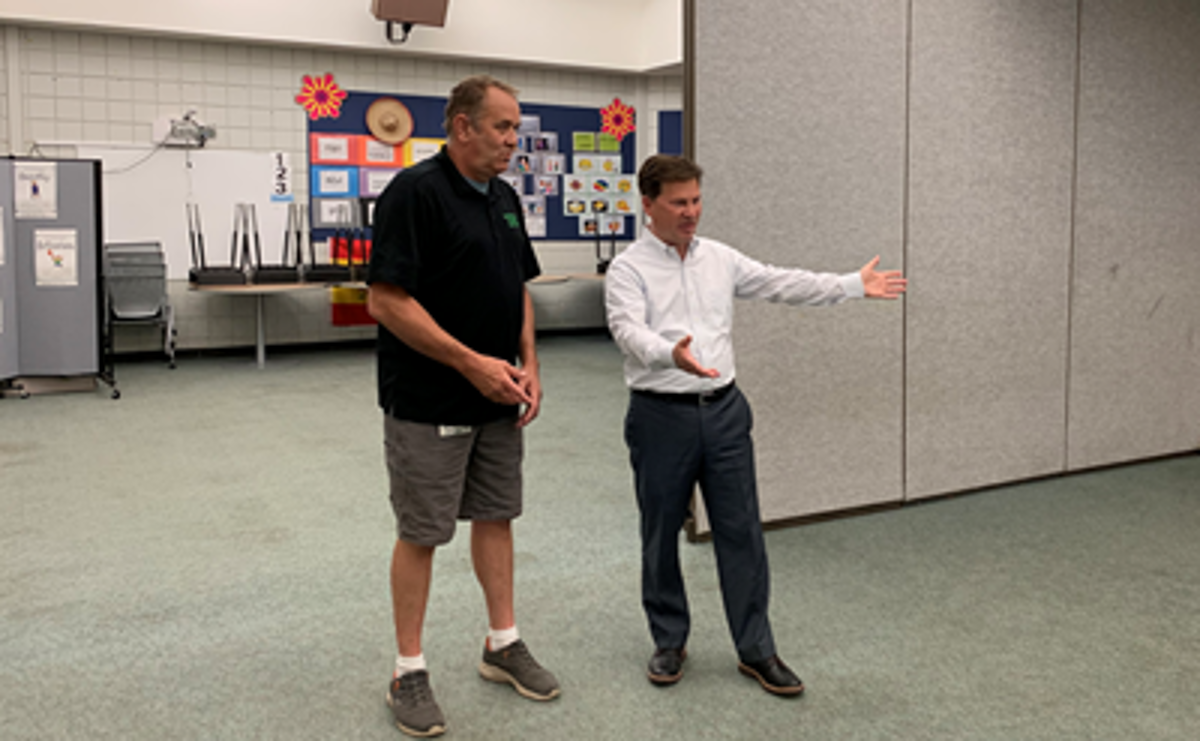 Two men standing next to each other talking. 